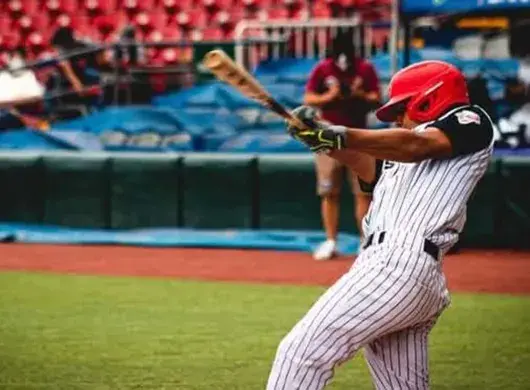 Estudiante bateando durante juego de liga de prospectos