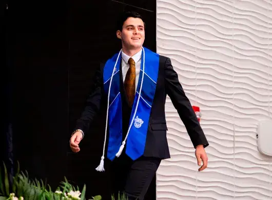 Alumno con estola del Tec de Monterrey avanza hacia la recepción de su título profesional en la graduación de la generación junio 2025