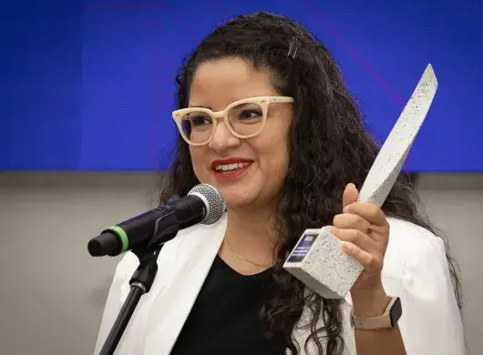 Mujer hablando y en la mano sostiene estatuilla del Premio Mujer Tec 2025.