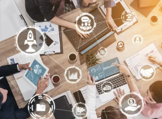 Equipo de emprendedores colaborando en una mesa con laptops, gráficas y herramientas digitales, analizando ideas de negocio y crecimiento