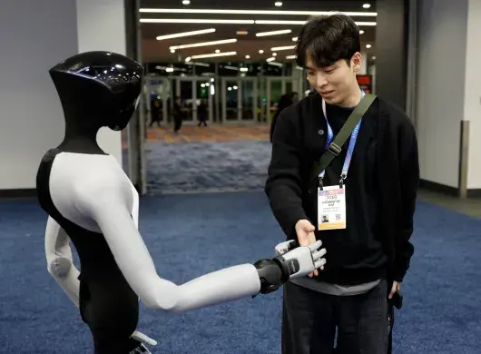 Un asistente estrecha la mano de un robot humanoide PaXini durante la Feria de Electrónica de Consumo (CES) 