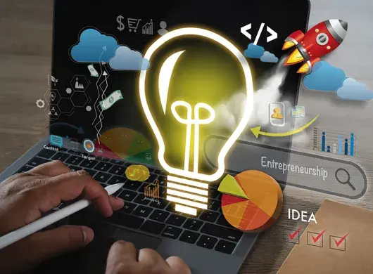 fotografía de una computadora con ilustraciones de bombilla de luz, cohete, ideas