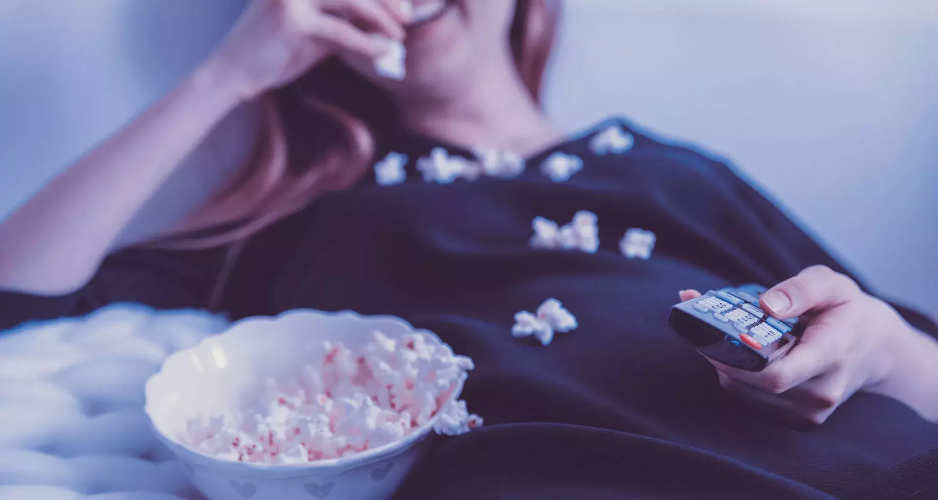 Chica comiendo palomitas viendo la TV