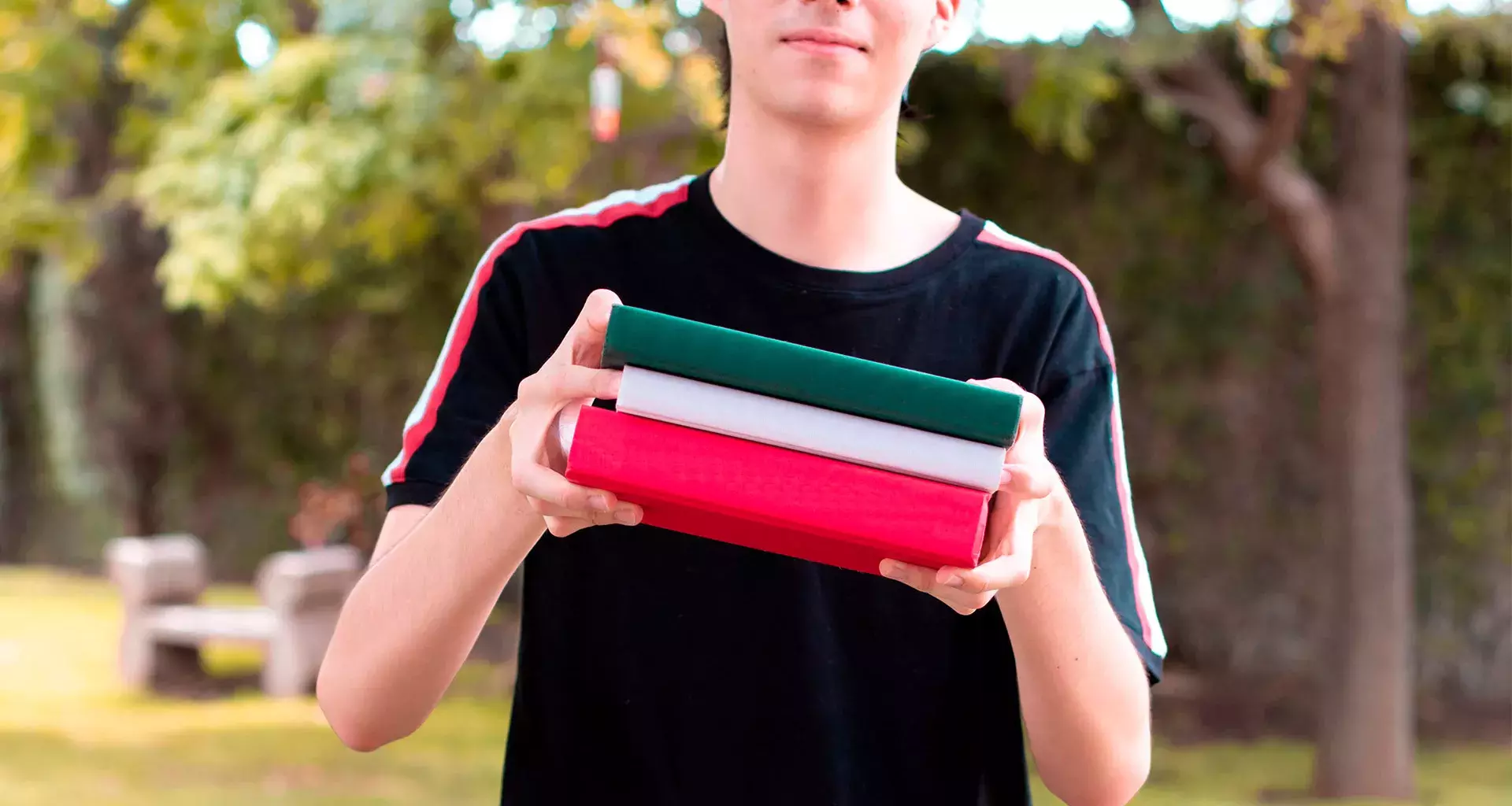 Joven sosteniendo libros verde, blanco y rojo