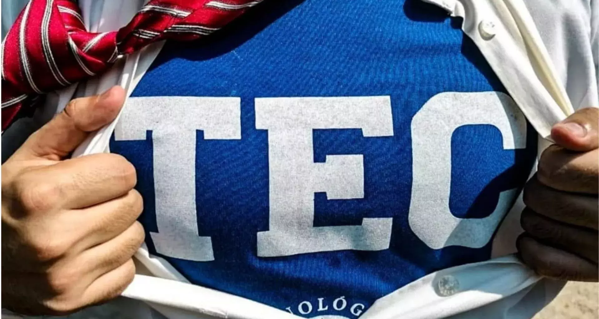 Persona que se abre la playera para poder apreciar la playera TEC de fondo.