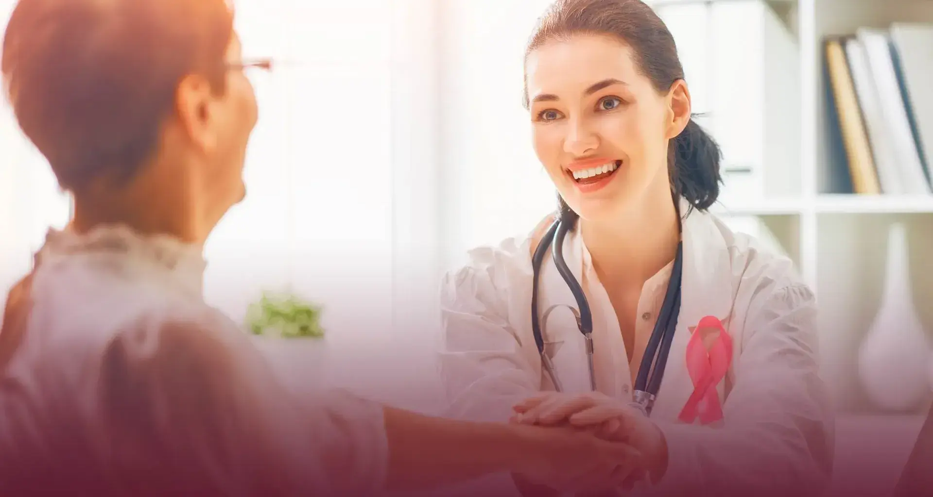 Doctora portando listón rosa y paciente, temática prevención cáncer de mama