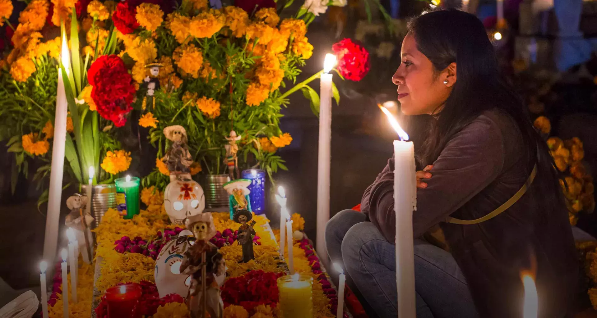 Mujer frente a ofrenda del Día de Muertos