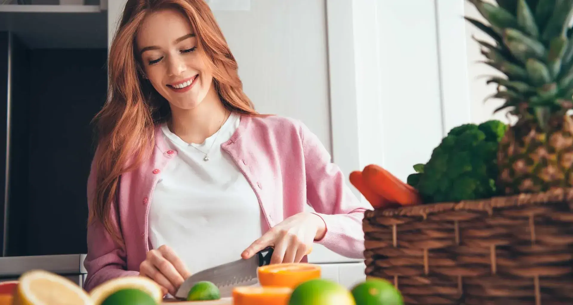 Mujer joven en una cocina cortado un limón con frutas y verduras