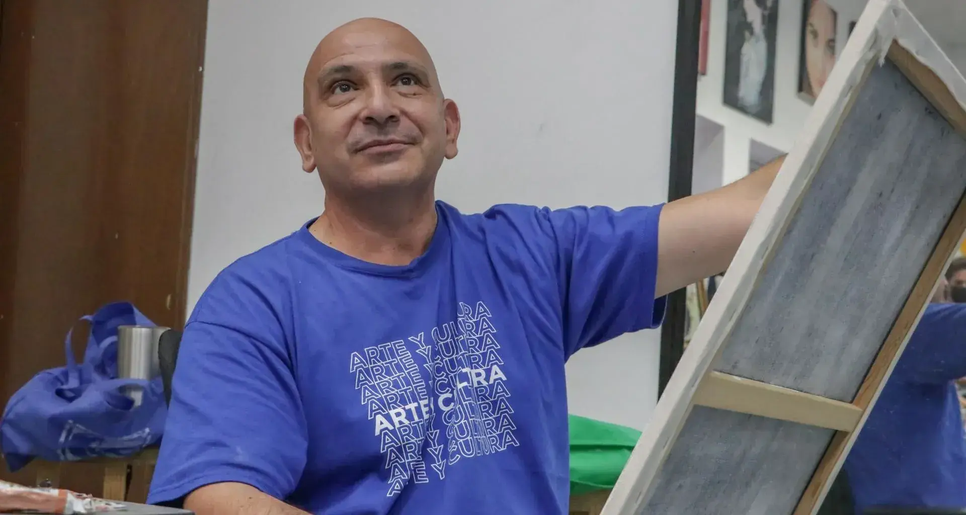 Profesor de artes plásticas pintando un cuadro con ligera sonrisa volteando hacia arriba.