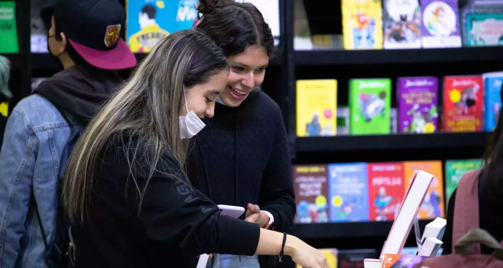 Dos mujeres jóvenes buscan libros en la FIL Monterrey 2022