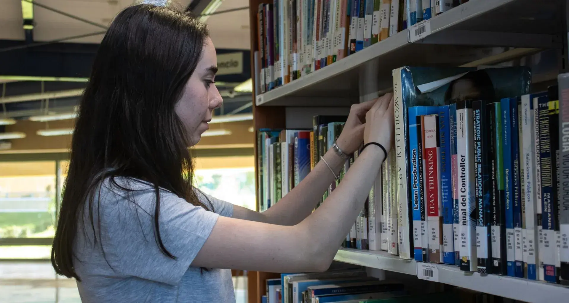 Lucía Oria, ganadora de la beca, busca entre libros en la biblioteca 