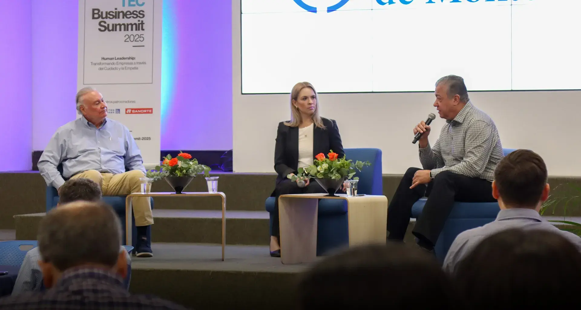 Dos hombres y una mujer platicando en escenario como parte de un foro.