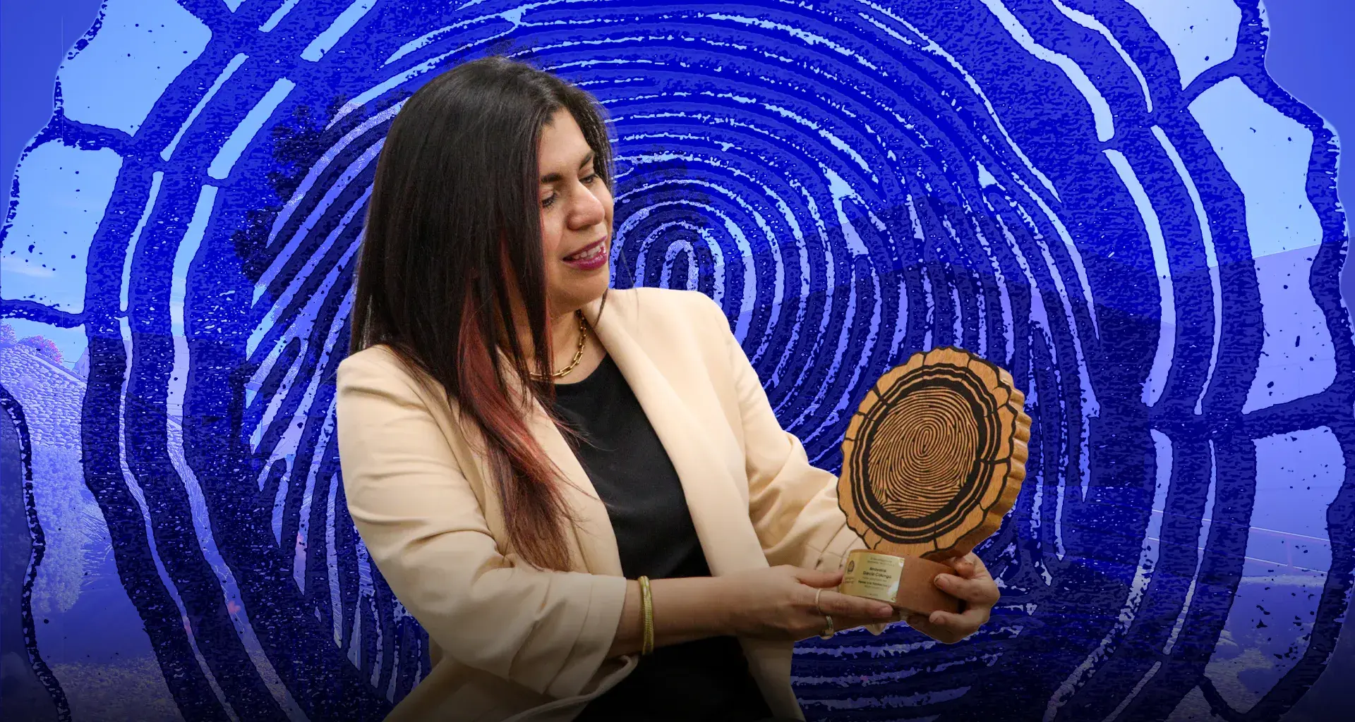 Mujer con saco blanco sosteniendo trofeo con forma de corte transversal de tronco y mirando hacia el.