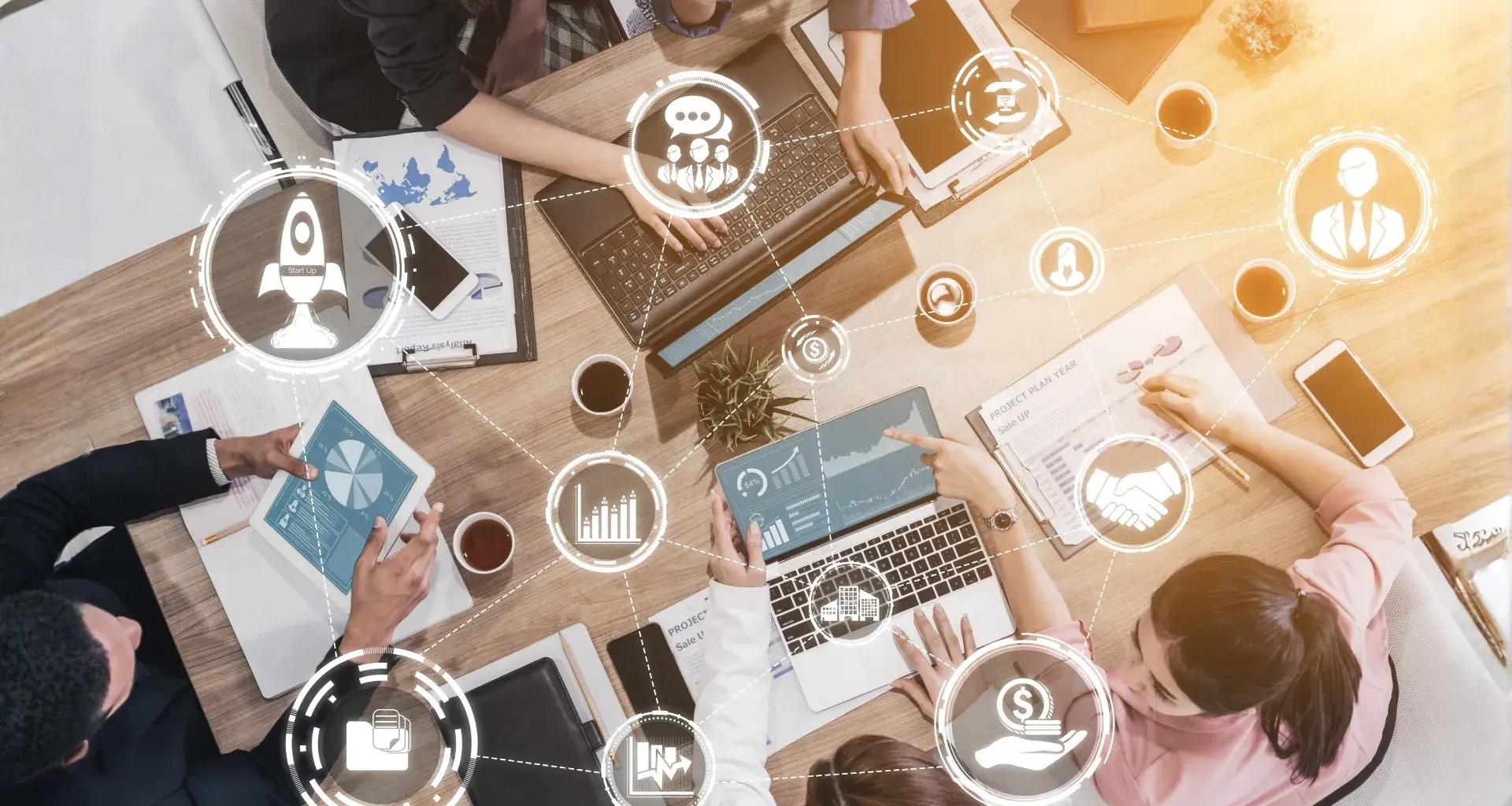 Equipo de emprendedores colaborando en una mesa con laptops, gráficas y herramientas digitales, analizando ideas de negocio y crecimiento