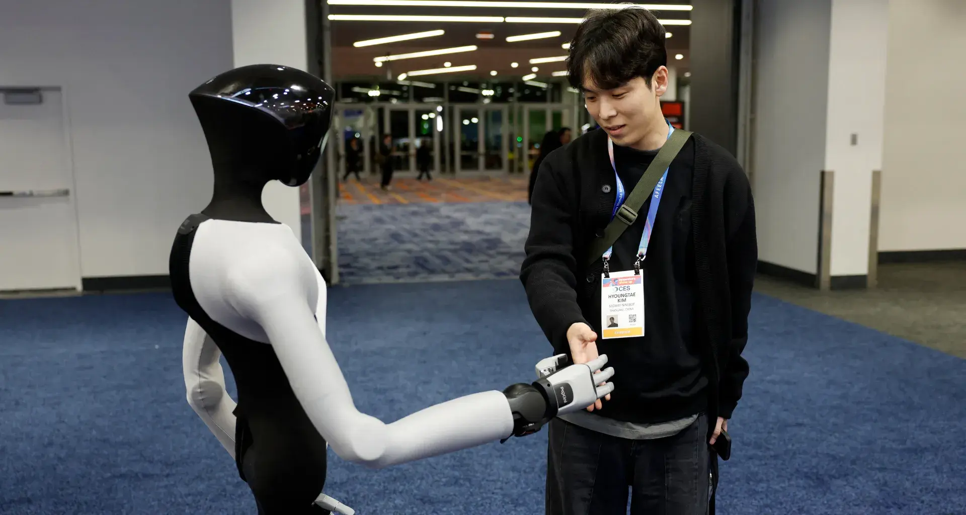 Un asistente estrecha la mano de un robot humanoide PaXini durante la Feria de Electrónica de Consumo (CES) 