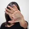 Mujer con palma de la mano abierta, en señal de poner un alto a la violencia de género