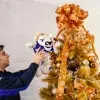 Alumno del Tec campus Toluca colocando peluche de Teus en árbol de Navidad