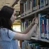 Lucía Oria, ganadora de la beca, busca entre libros en la biblioteca 