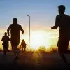 Personas corriendo a contraluz con el amanecer en el fondo