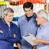 Tres generaciones de hombres platicando en una ferretería, concepto de una empresa familiar