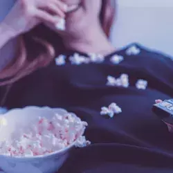 Chica comiendo palomitas viendo la TV