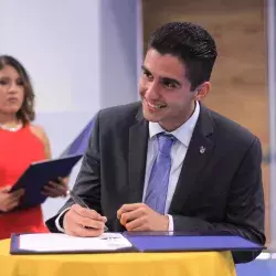 Estudiante Raul Maya de la carrera de Ingeniería Industrial firmando su título. 