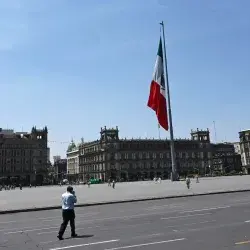 Vista del Zócalo de la Ciudad de México, con una persona caminando por su calle ante el vacío de vehículos