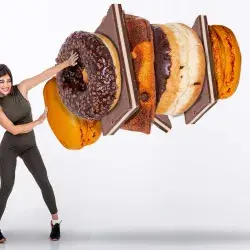 Imagen conceptual de chica luchando contra unas donas gigantes y chocolates de comida