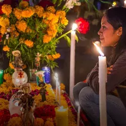 Mujer frente a ofrenda del Día de Muertos