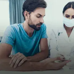 Hombre joven junto a doctora aplicando prueba de glucosa