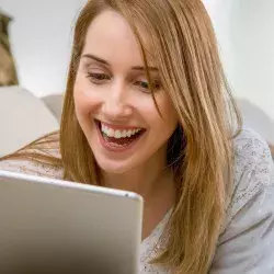 mujer mirando su tablet mientras sonríe