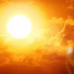 Fotografía del sol reflejando sus rayos en el cielo con tonalidades rojizas/naranjas por altas temperaturas.