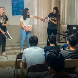 Estudiantes enseñando ciencia frente a un grupo. 