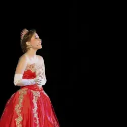 Anastasia cantando, usa un vestido rojo y una corona