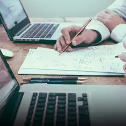 Superficie de una mesa con laptops y papeles.