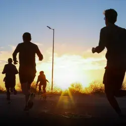 Personas corriendo a contraluz con el amanecer en el fondo