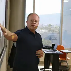 Profesor de PrepaTec Laguna imparte clase con proyector y apunta al pintarrón con su mano derecha