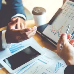 Personas analizando gráficos y datos financieros