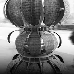 Foto en blanco y negro de la escultura con una persona caminando en el fondo.