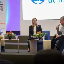 Dos hombres y una mujer platicando en escenario como parte de un foro.