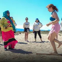 Adolescente hace baile tradicional guiada por un miembro de la comunidad Comca'ac en la playa.