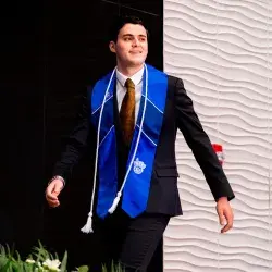 Alumno con estola del Tec de Monterrey avanza hacia la recepción de su título profesional en la graduación de la generación junio 2025