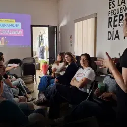 Mujer dando una platica frente a un grupo de mujeres jóvenes.
