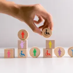 Mano acomoda bloques de madera con iconos que representan la diversidad de personas en la sociedad.