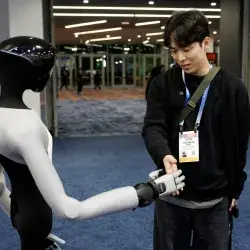 Un asistente estrecha la mano de un robot humanoide PaXini durante la Feria de Electrónica de Consumo (CES) 