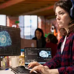 estudiante universitaria con audifonos viendo varias pantallas 