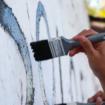 Alumnos y Armando Alanís pintando paredes con frases poéticas