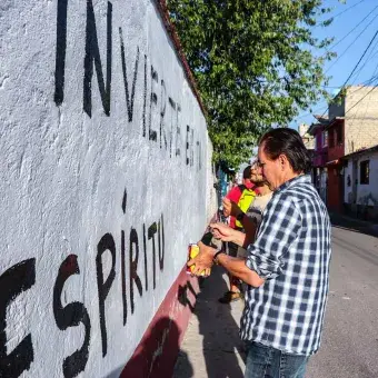 Alumnos y Armando Alanís pintando paredes con frases poéticas