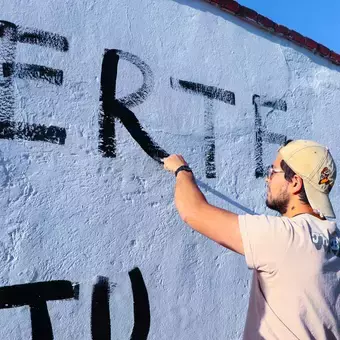 Alumnos y Armando Alanís pintando paredes con frases poéticas