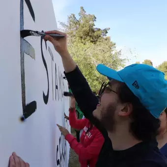 Alumnos y Armando Alanís pintando paredes con frases poéticas